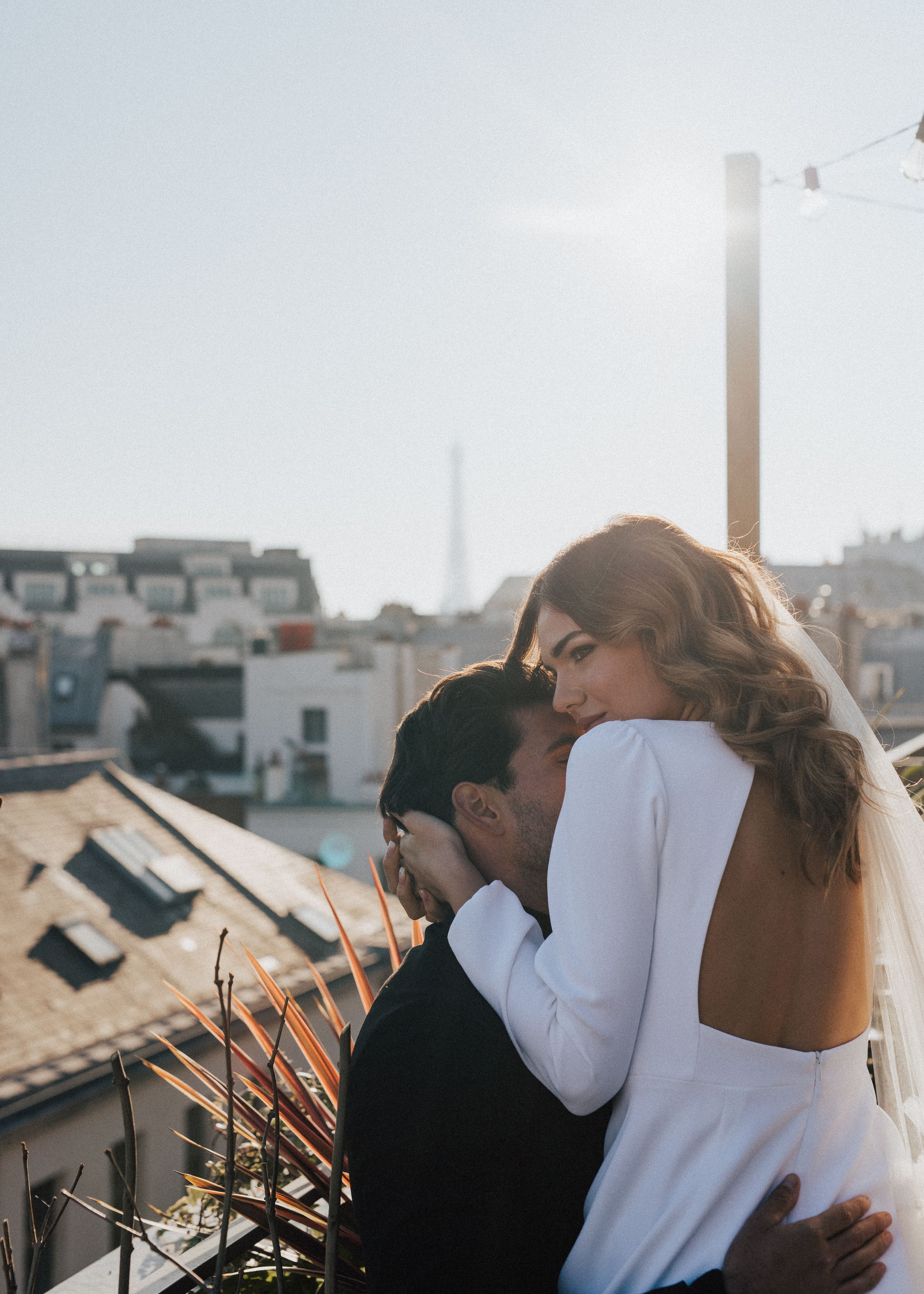 Tender moments captured between couple on urban rooftop at sunset.