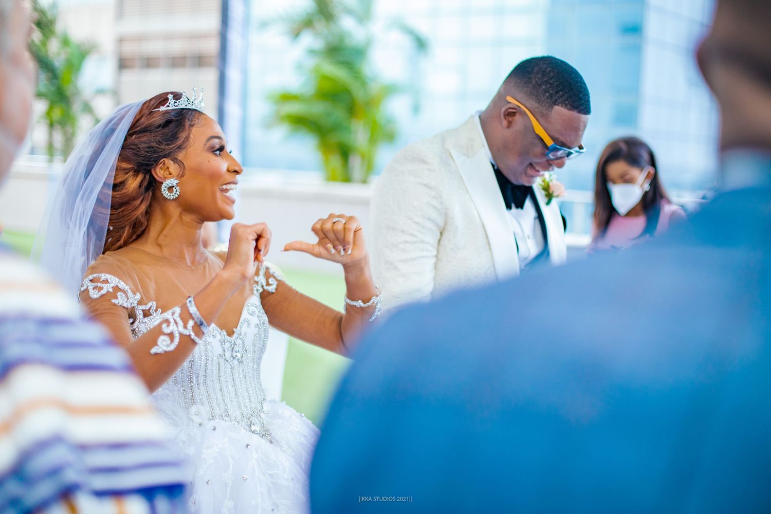 Wedding ceremony attendees seated outdoors under white floral arrangements.