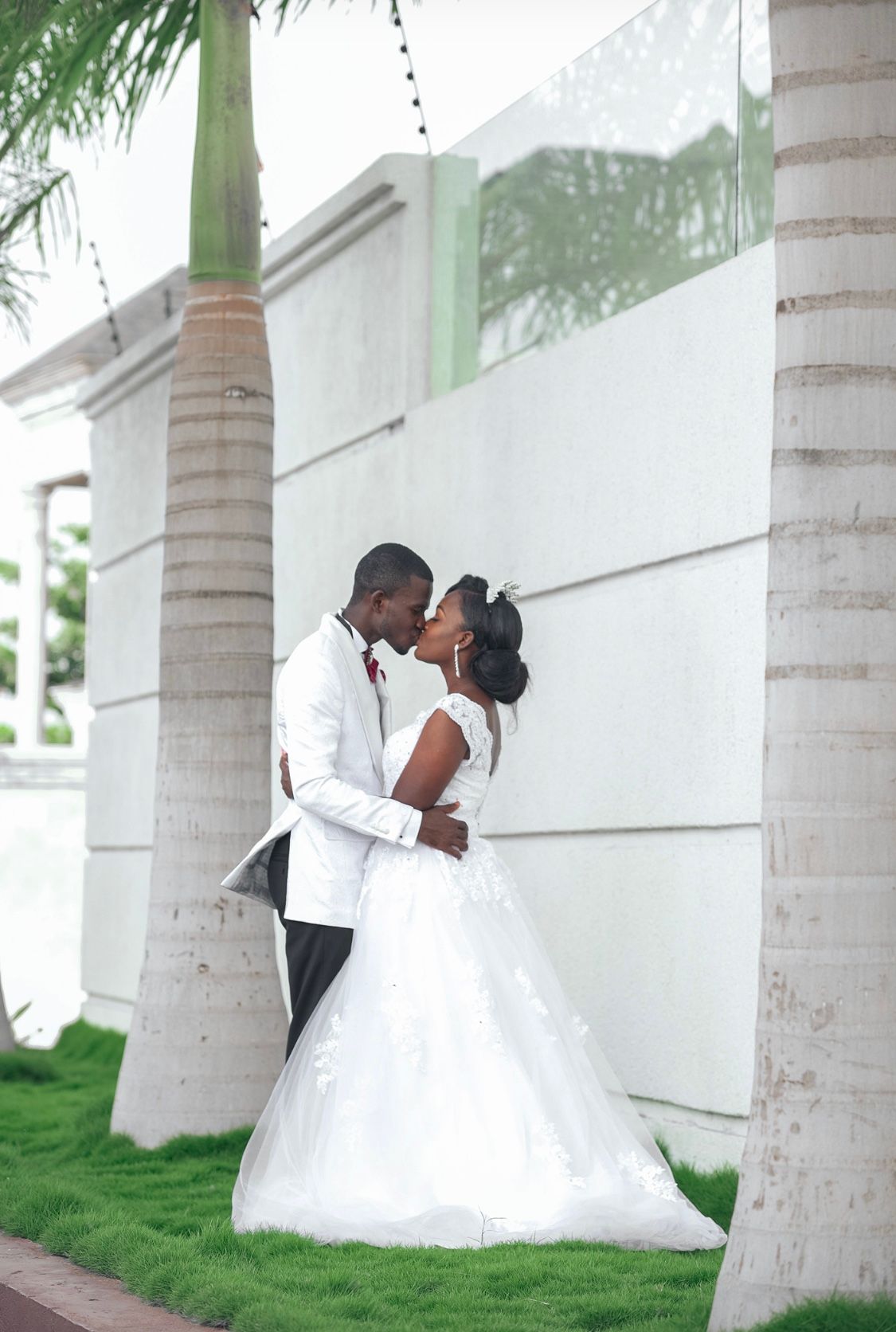 Romantic wedding couple shares intimate moment among palm trees.