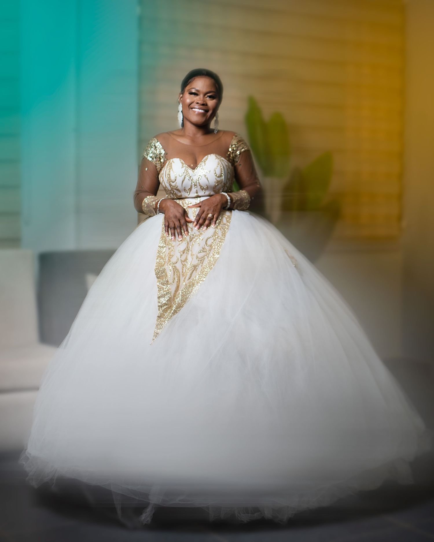 Elegant bridal portrait featuring flowing white ballgown with gold accents against colorful backdrop.