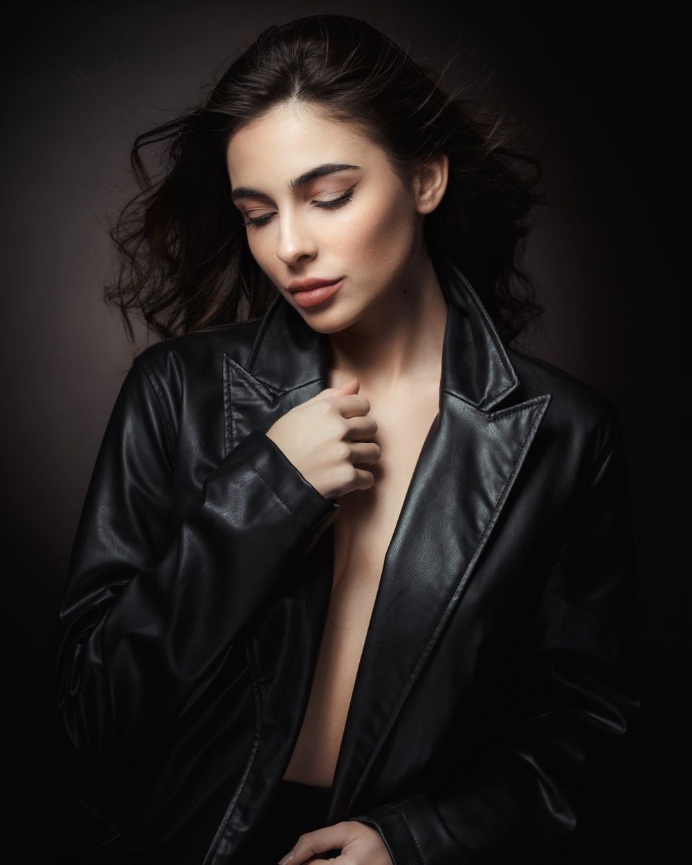 Moody fashion portrait featuring black leather jacket and dramatic lighting.