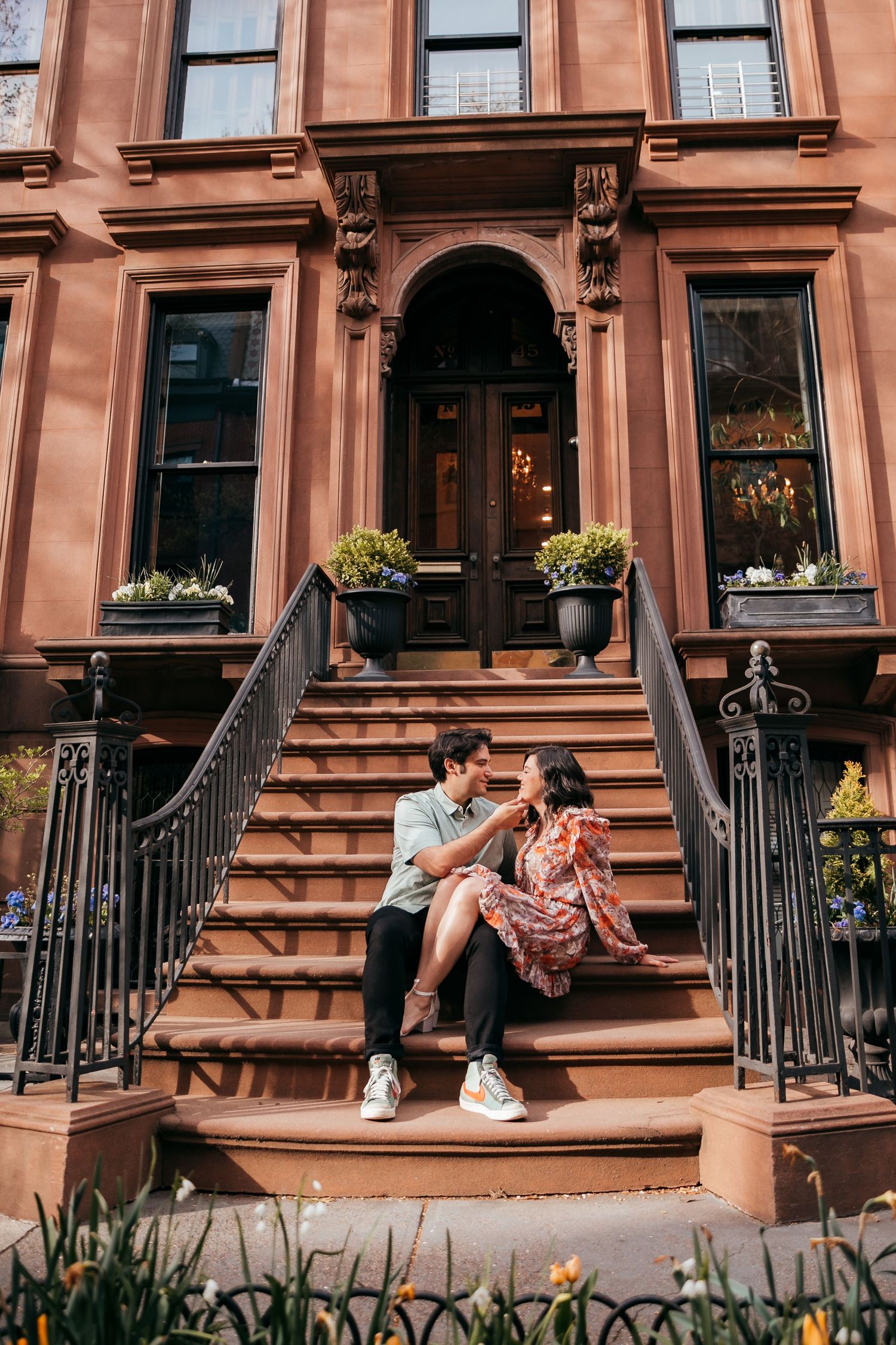 A loving couple shares a tender moment sitting on elegant brownstone steps.