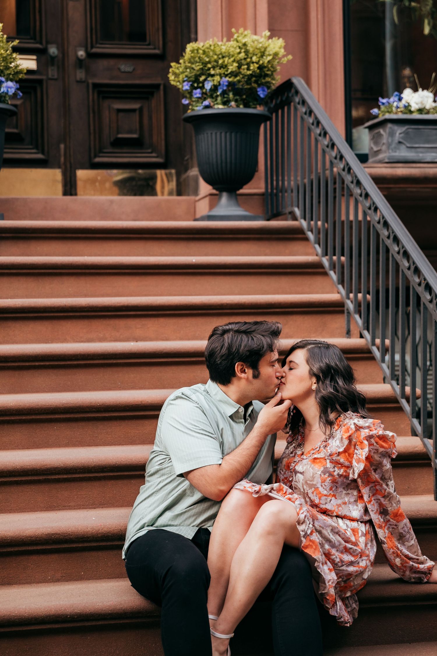 A couple shares a sweet kiss on the steps of a NYC brownstone.