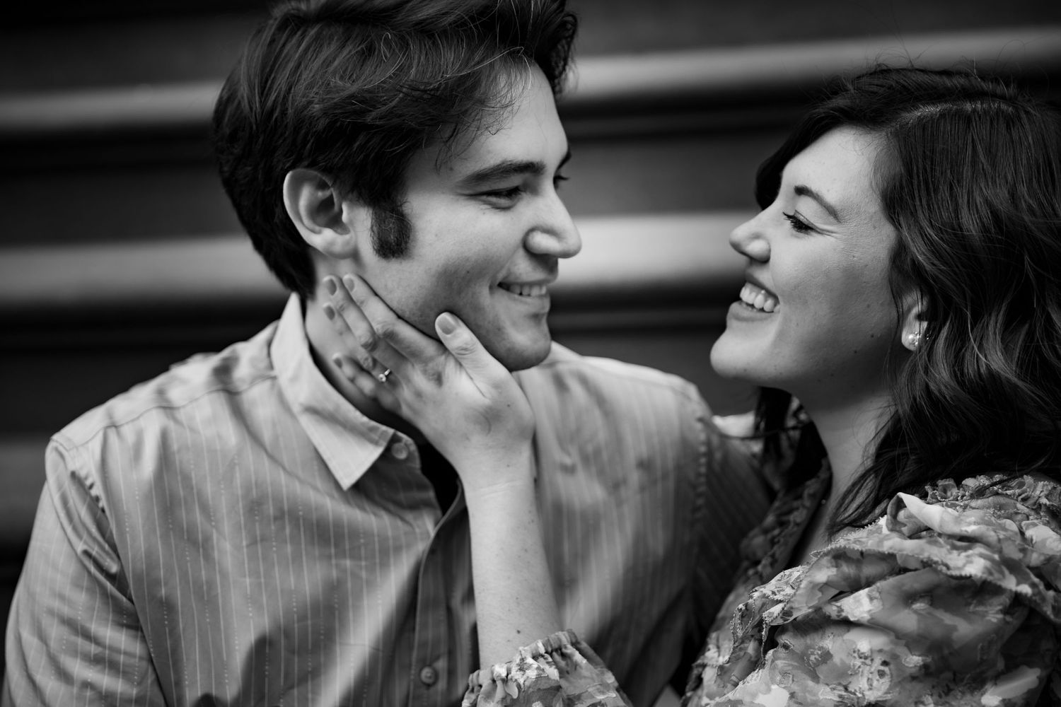 A black and white close-up of a smiling couple sharing a joyful moment.