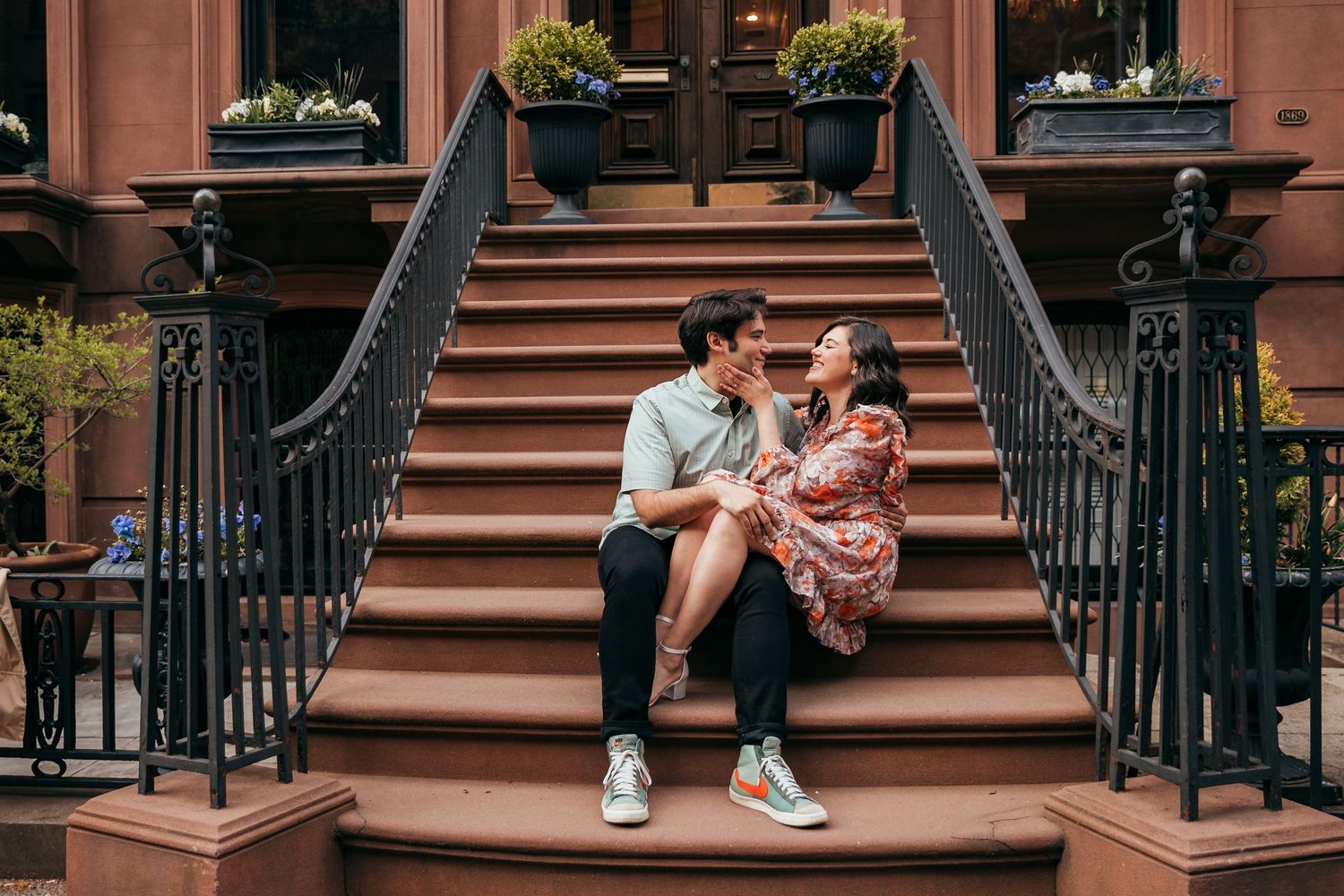 Couple sitting close together on elegant brownstone stoop steps in New York City neighborhood.