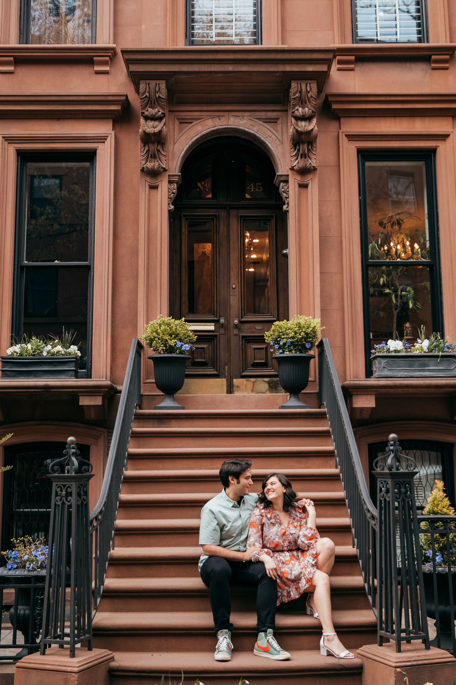 Couple sitting together on ornate brownstone steps, sharing a tender moment in New York City.