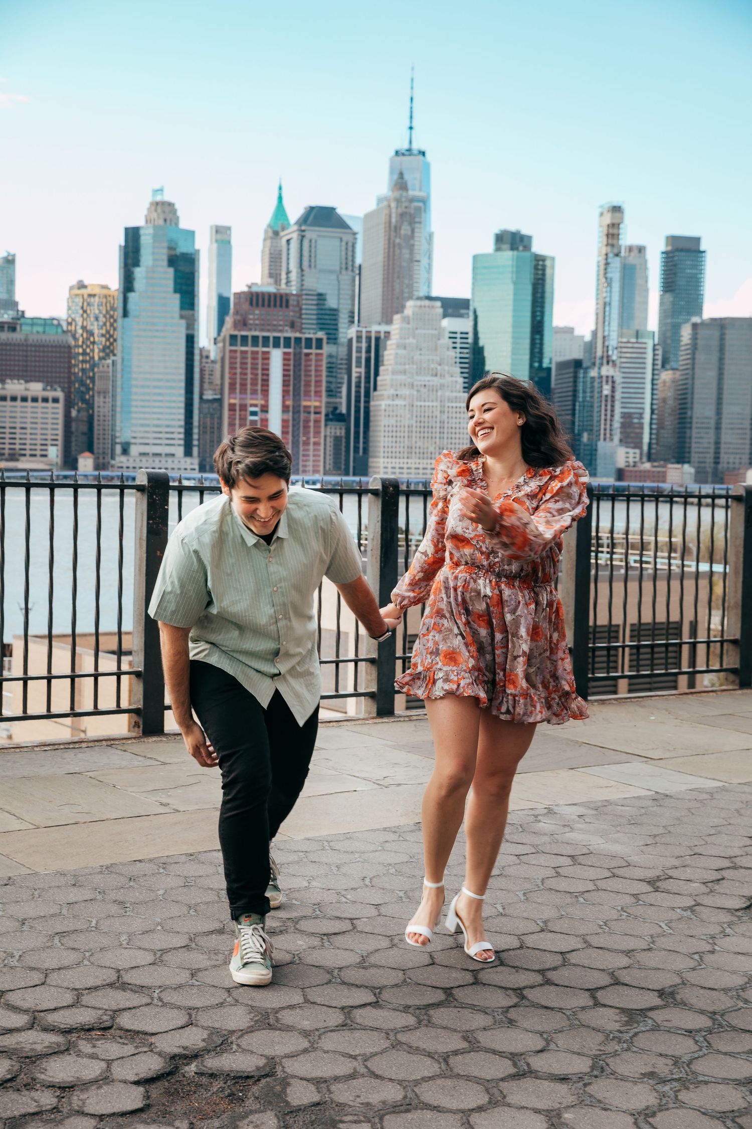 Joyful couple playing and holding hands with stunning NYC skyscraper skyline background.