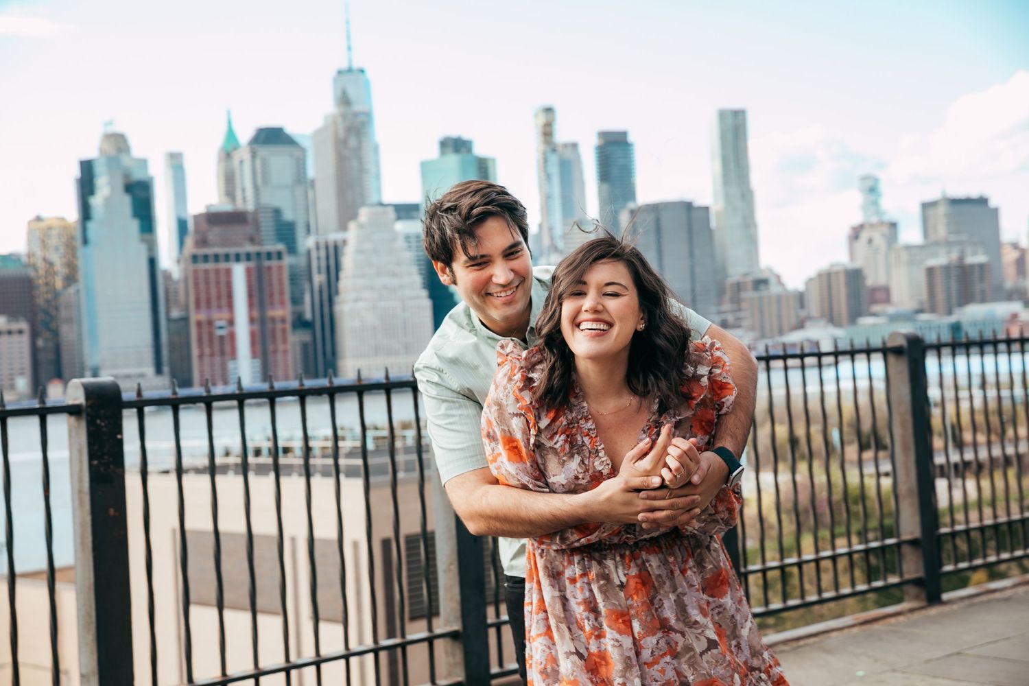Happy couple hugging and smiling with Manhattan skyline on a bright sunny day.