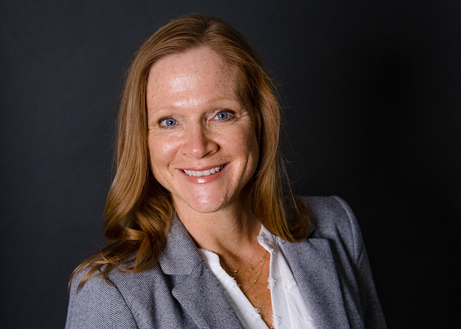 Professional headshot against dark background with studio lighting.