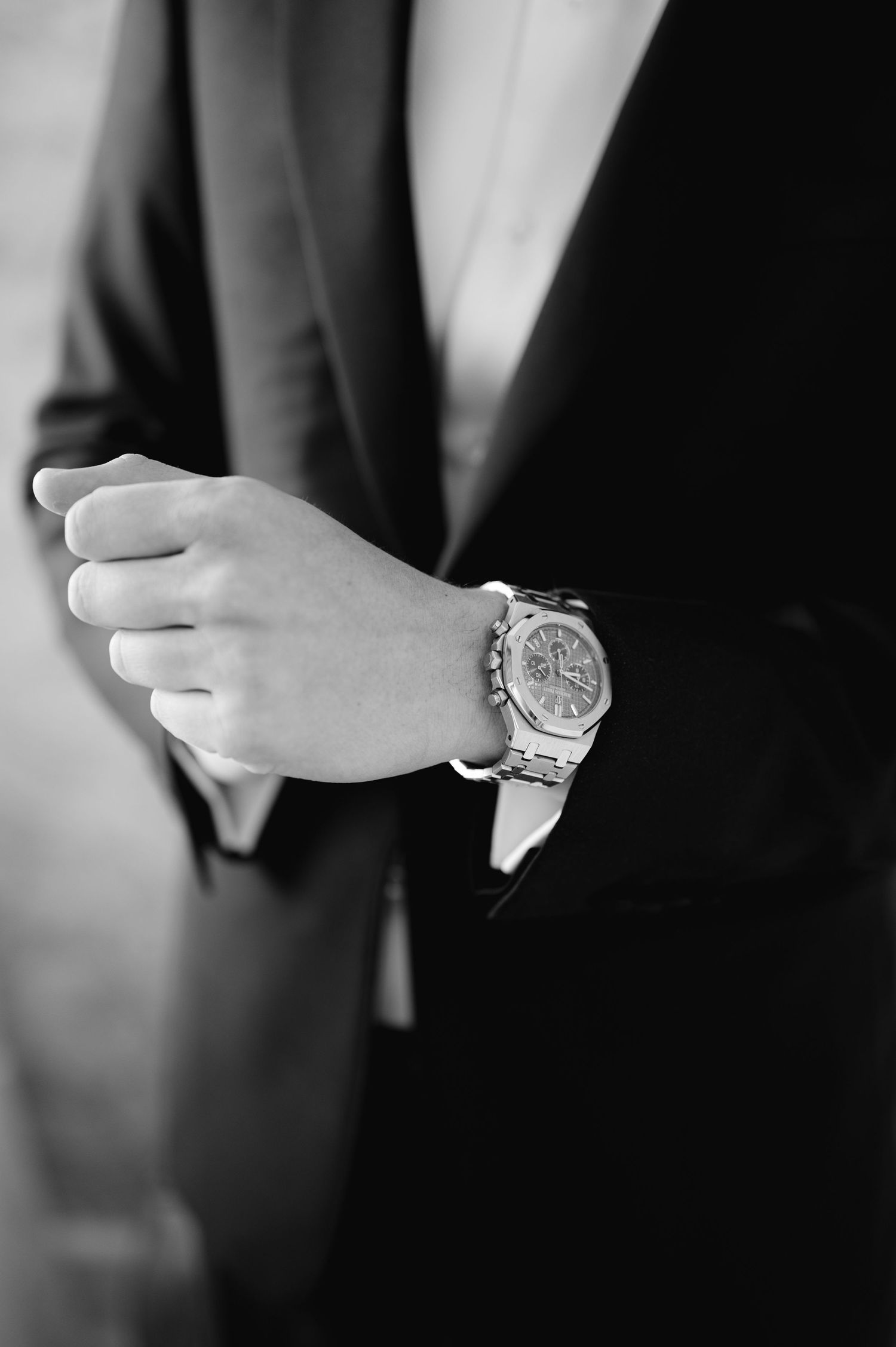 Close-up black and white photo of a luxury watch on a suited wrist.