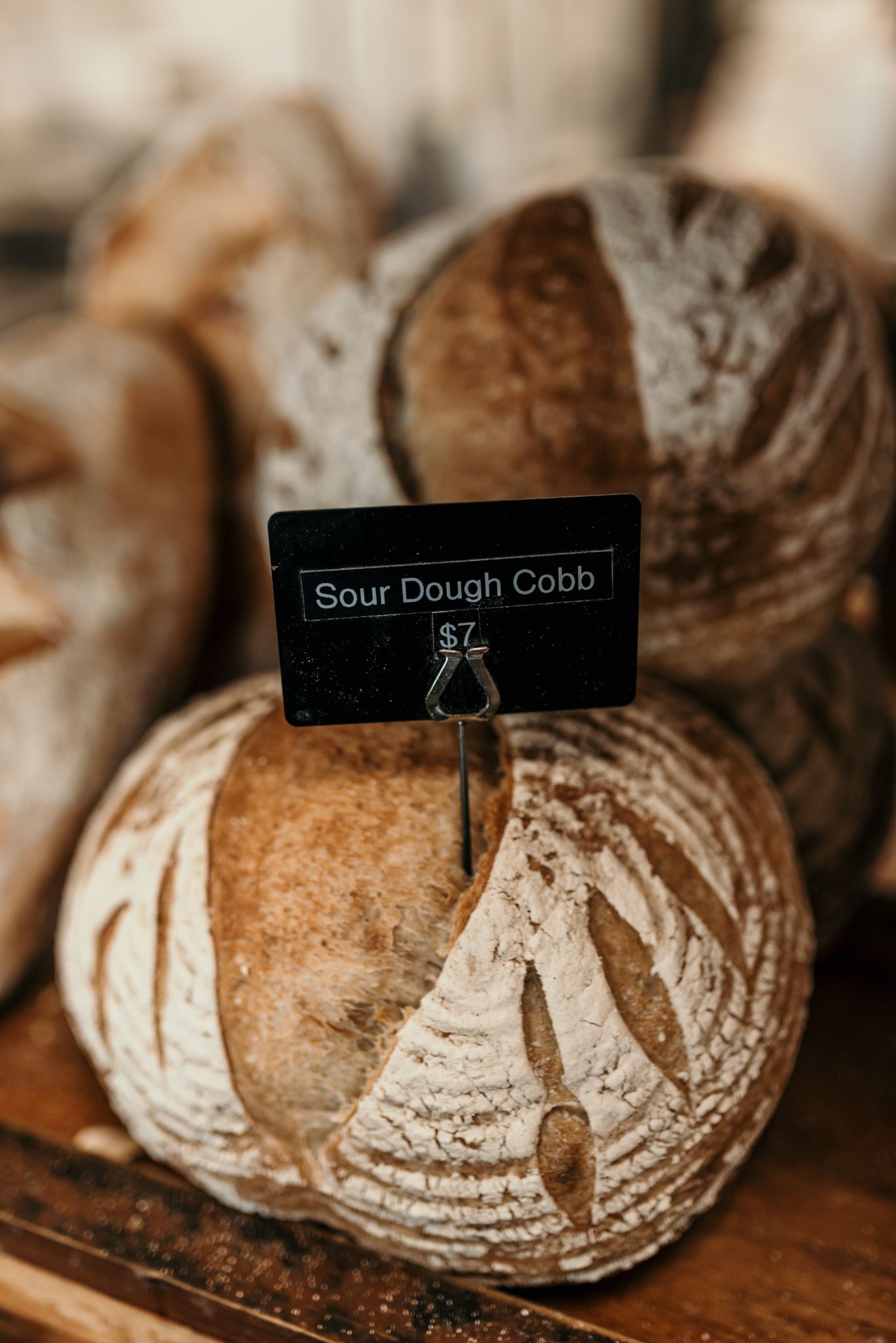 Fresh artisanal sourdough bread loaf with label marker in rustic bakery display.