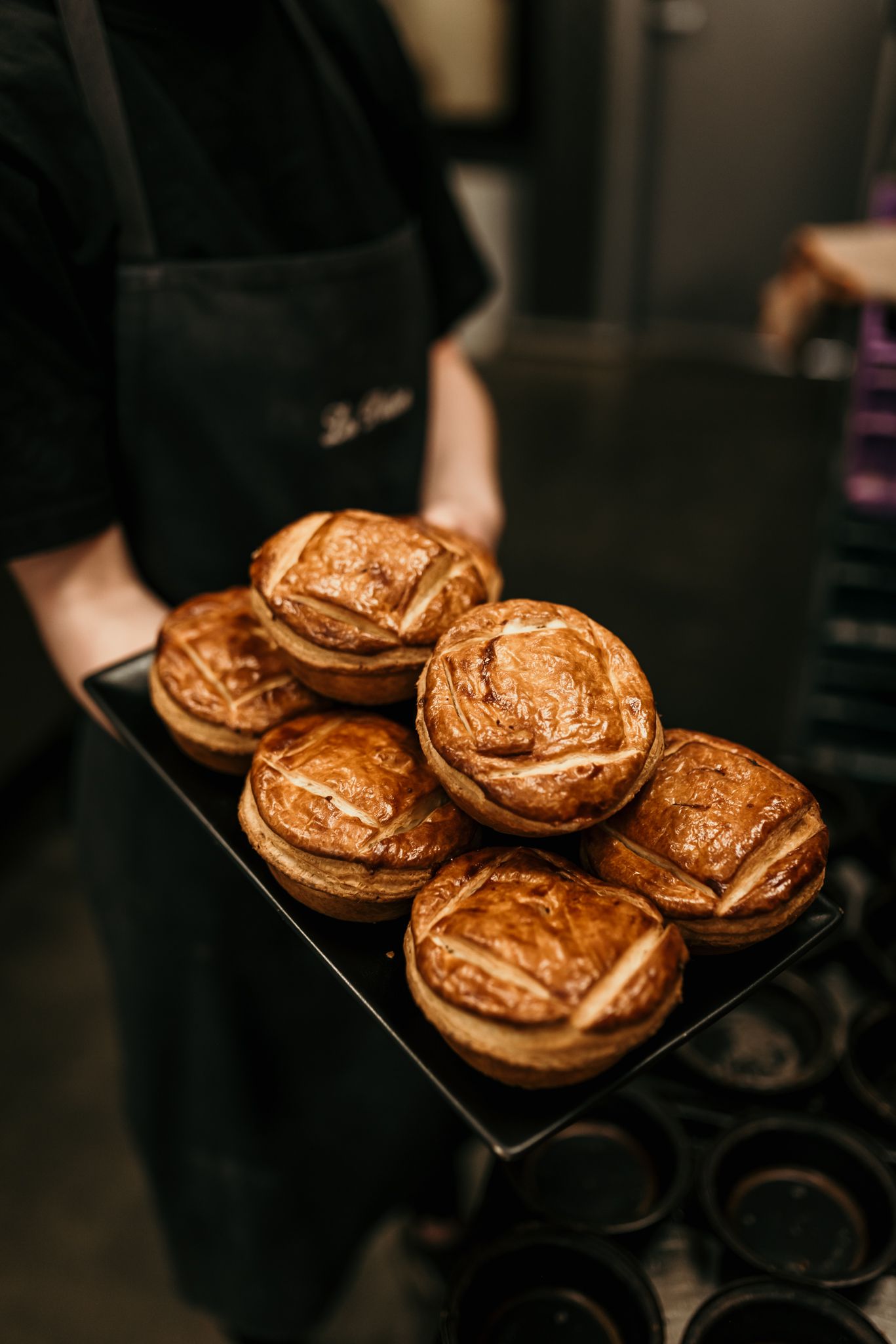 Golden brown galette pastries arranged on a dark serving tray.