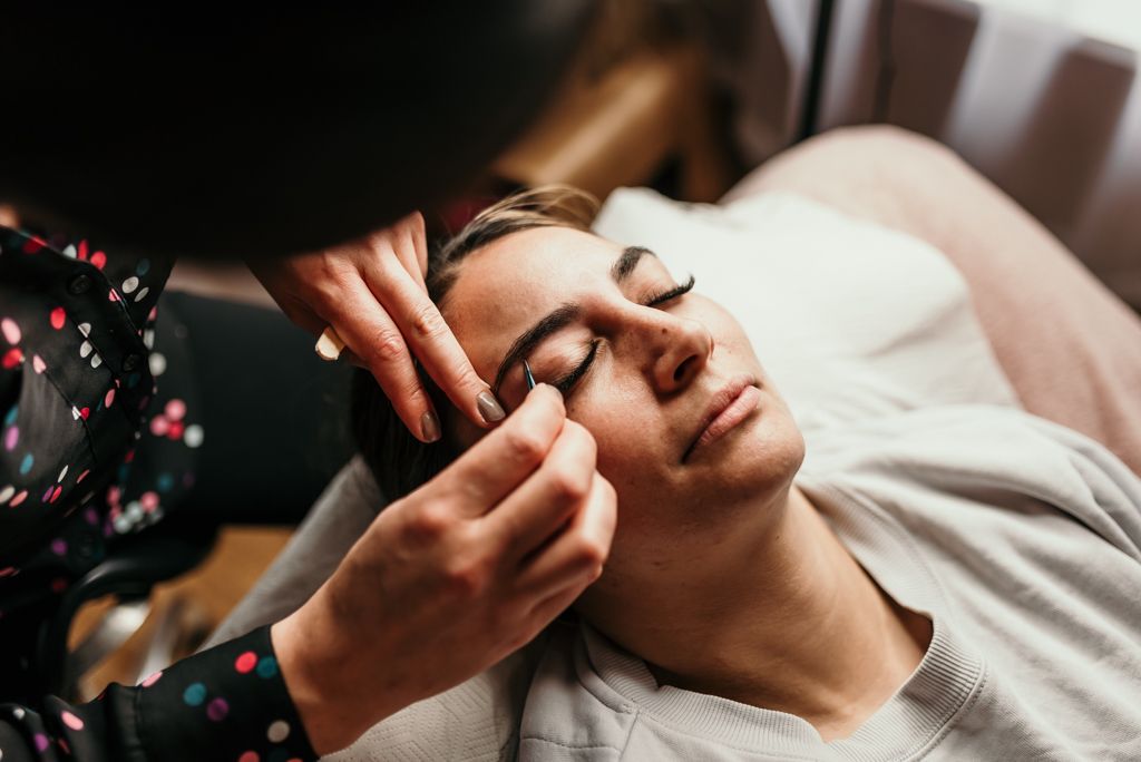 Hands applying eye treatment during a facial spa service.
