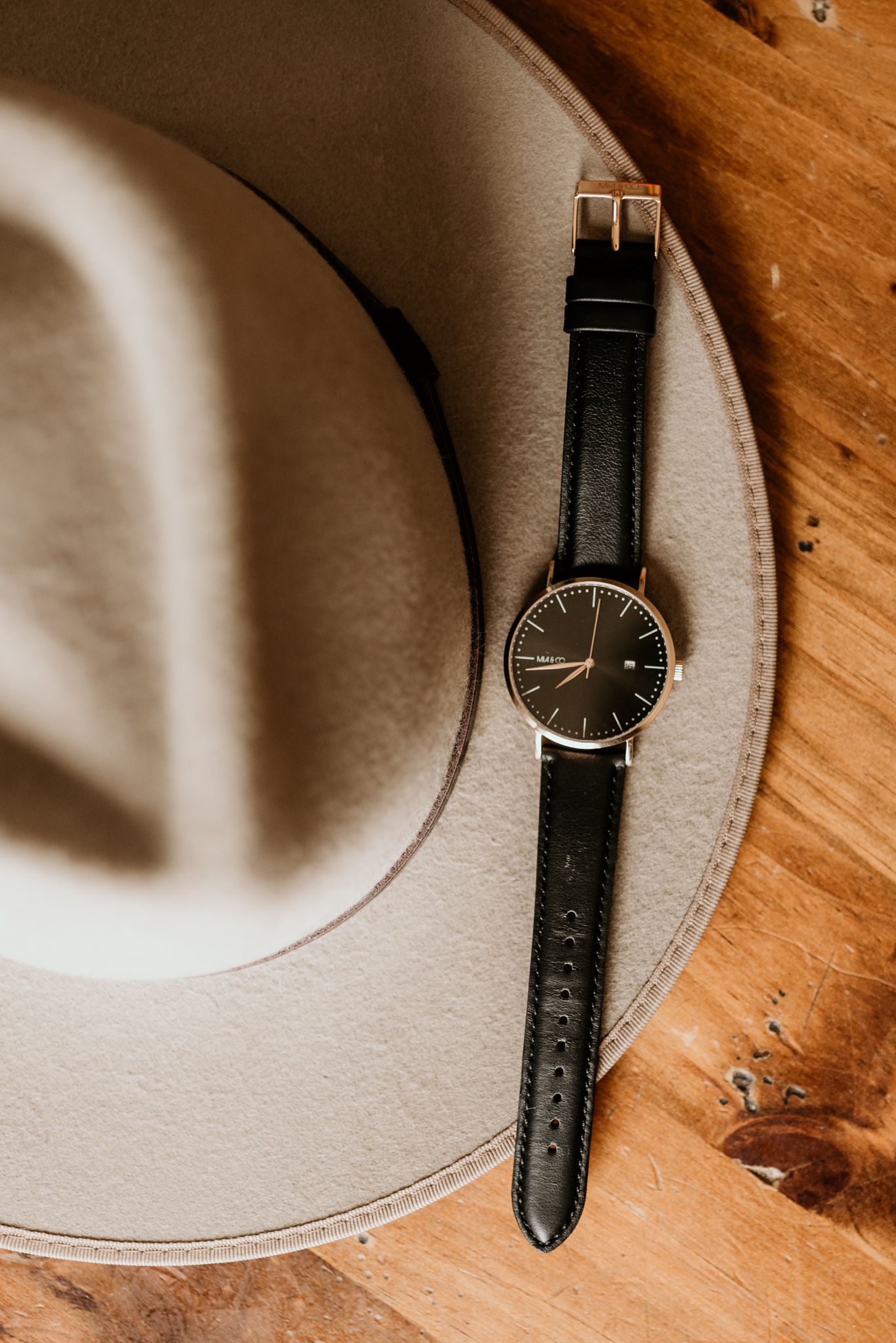 Classic black leather watch displayed on a grey felt hat.