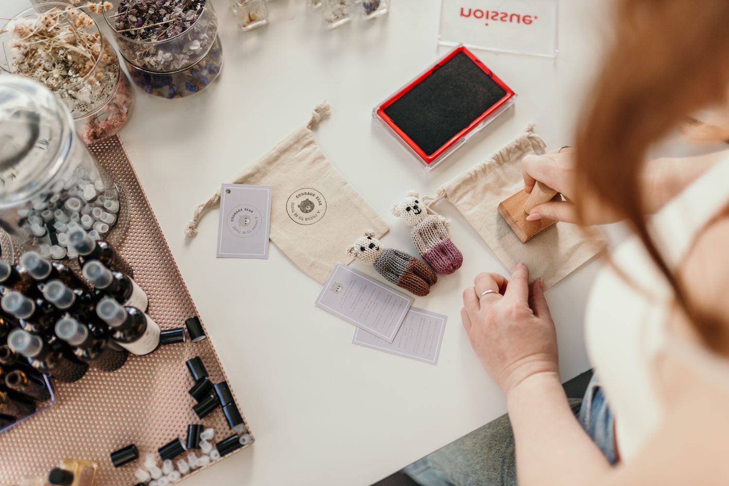 Flatlay of crafting supplies and cards with hands working on a project.