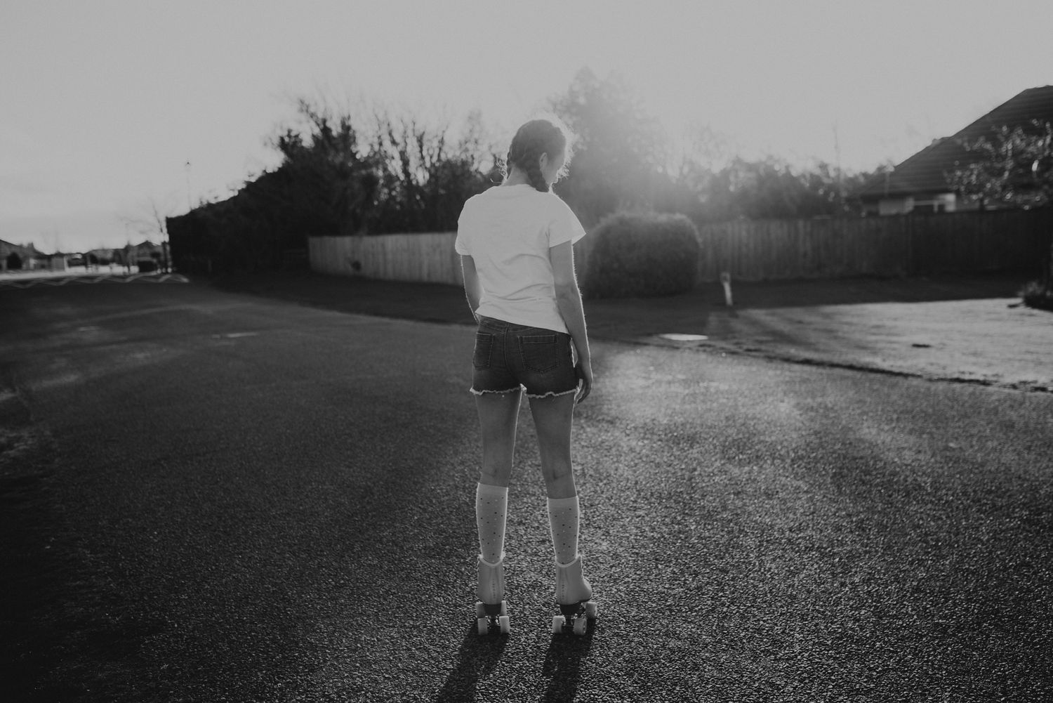 Silhouette of a skater standing on empty street at dusk.