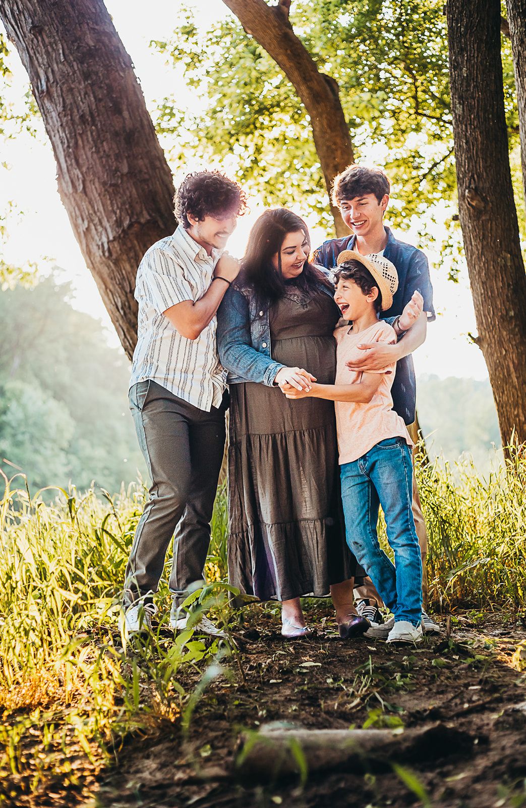 Family group enjoying playful moments together in sunlit wooded area.
