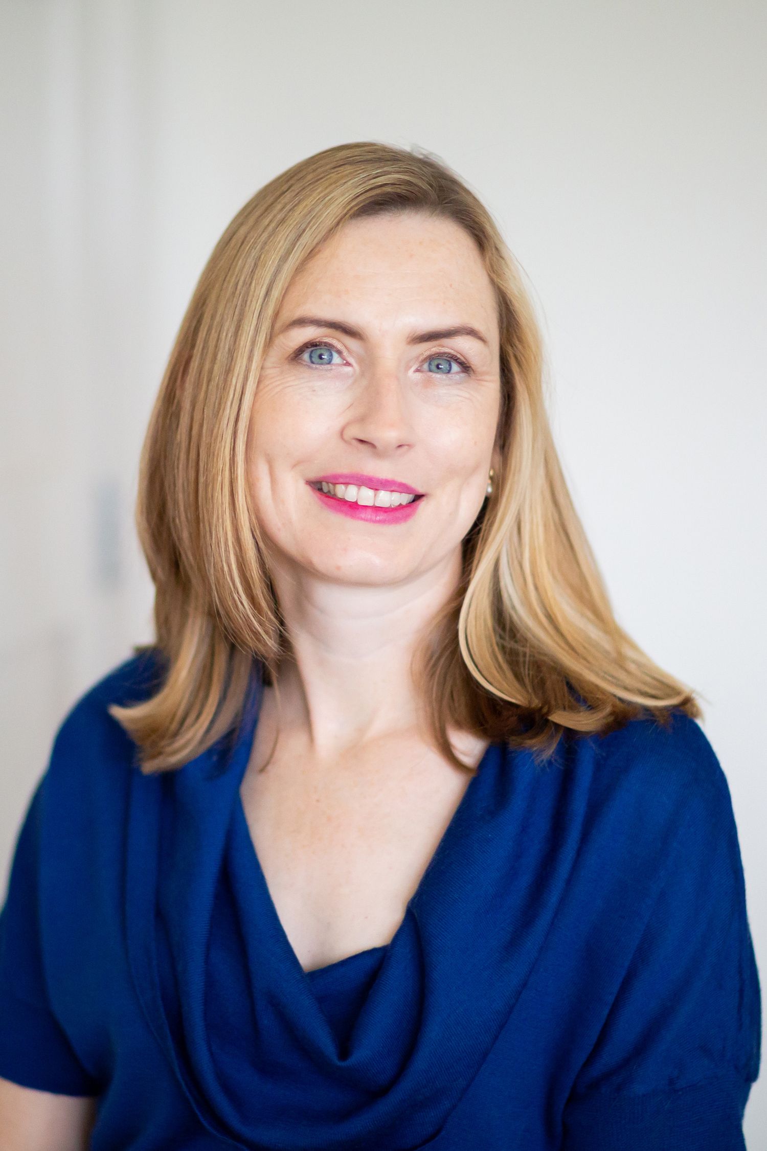 A professional headshot against a white background wearing a navy blue top during business branding photoshoot.