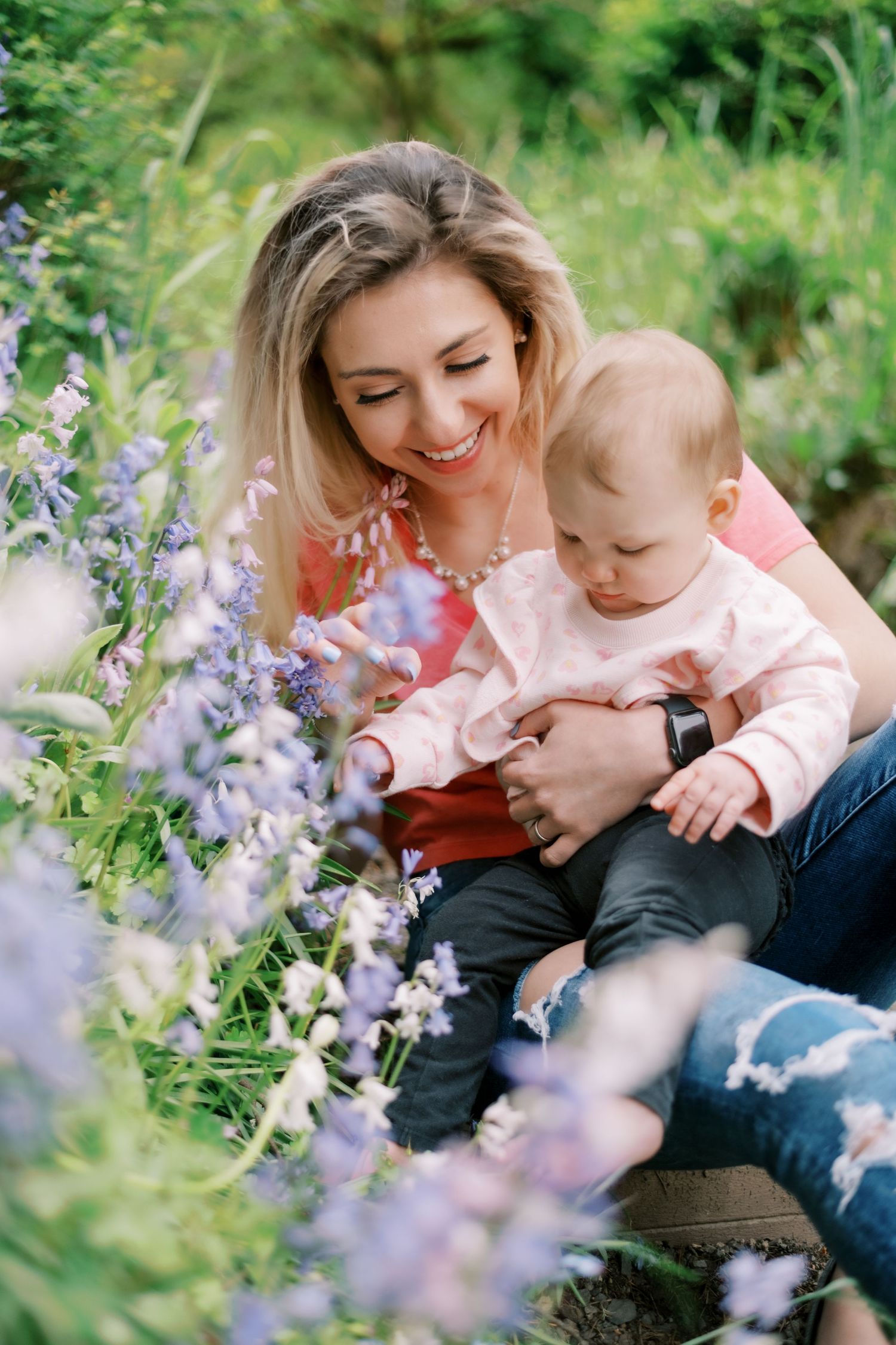 Sweet moment between mother and baby surrounded by purple wildflowers in garden.