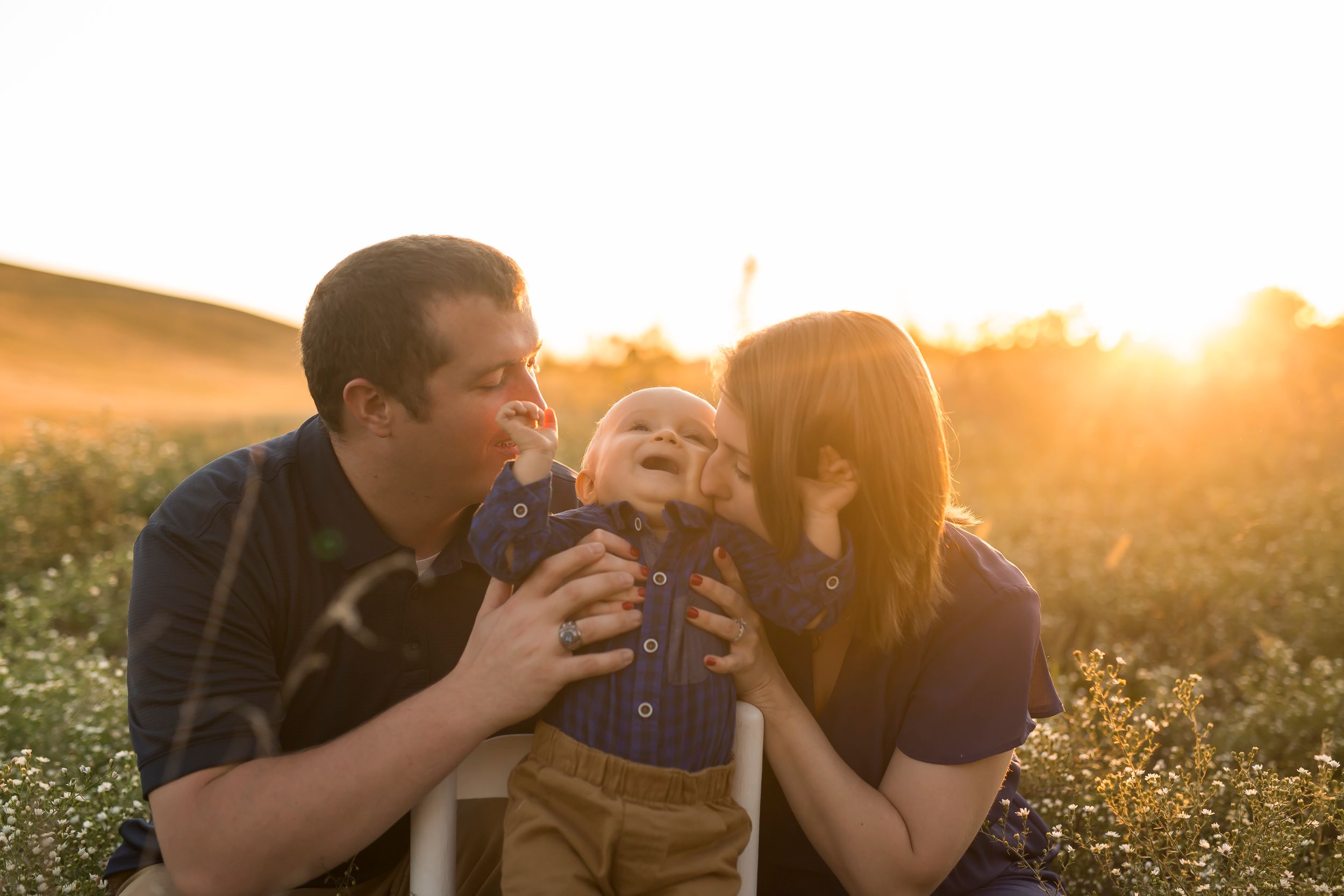 Family playing together in golden field at sunset.