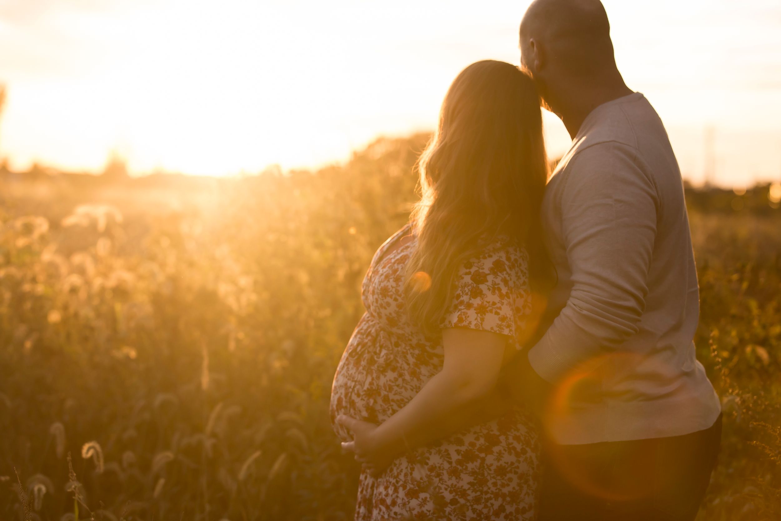 Silhouetted couple embracing in golden sunset light.