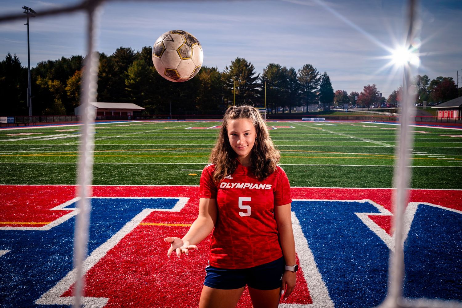Athletic field photography session featuring red and blue turf through goal posts.