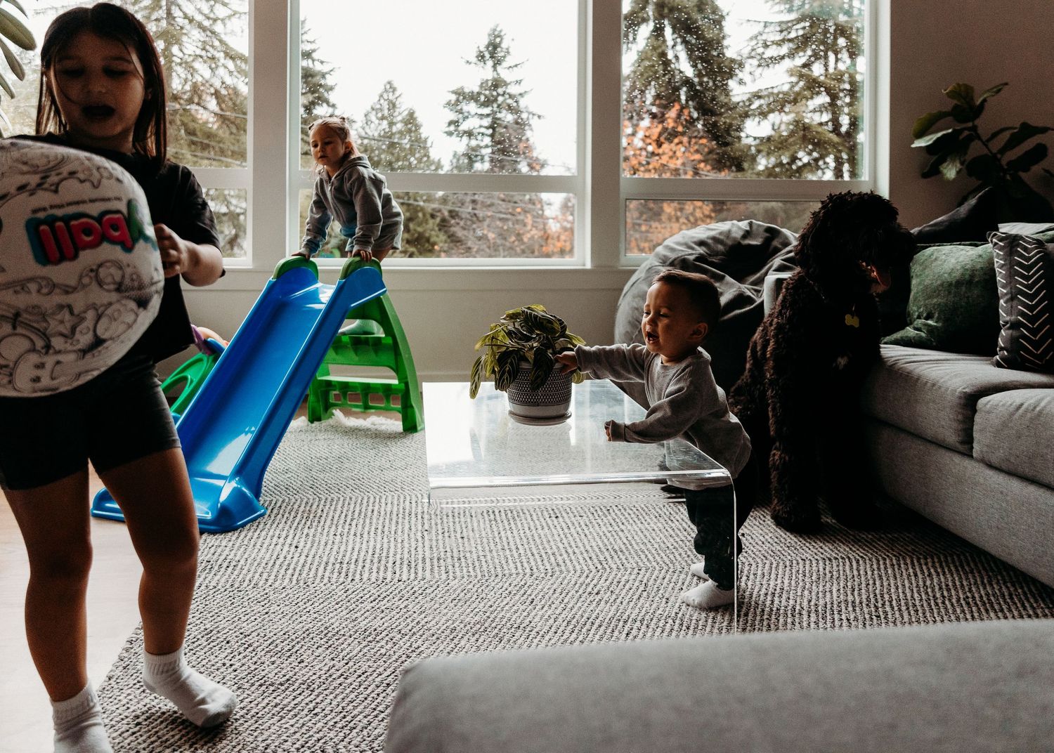 Indoor playtime with a blue slide and active movement in a sunlit living room.