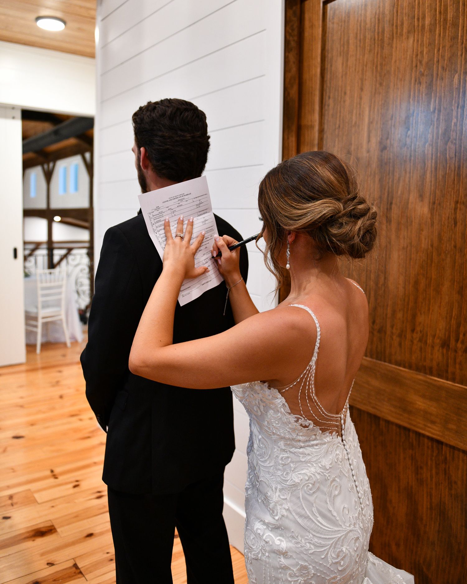 A tender moment between newlyweds standing by wooden doors in a rustic venue.