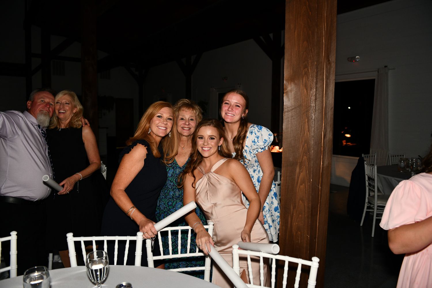 Wedding reception party with guests in formal attire around white Chiavari chairs.