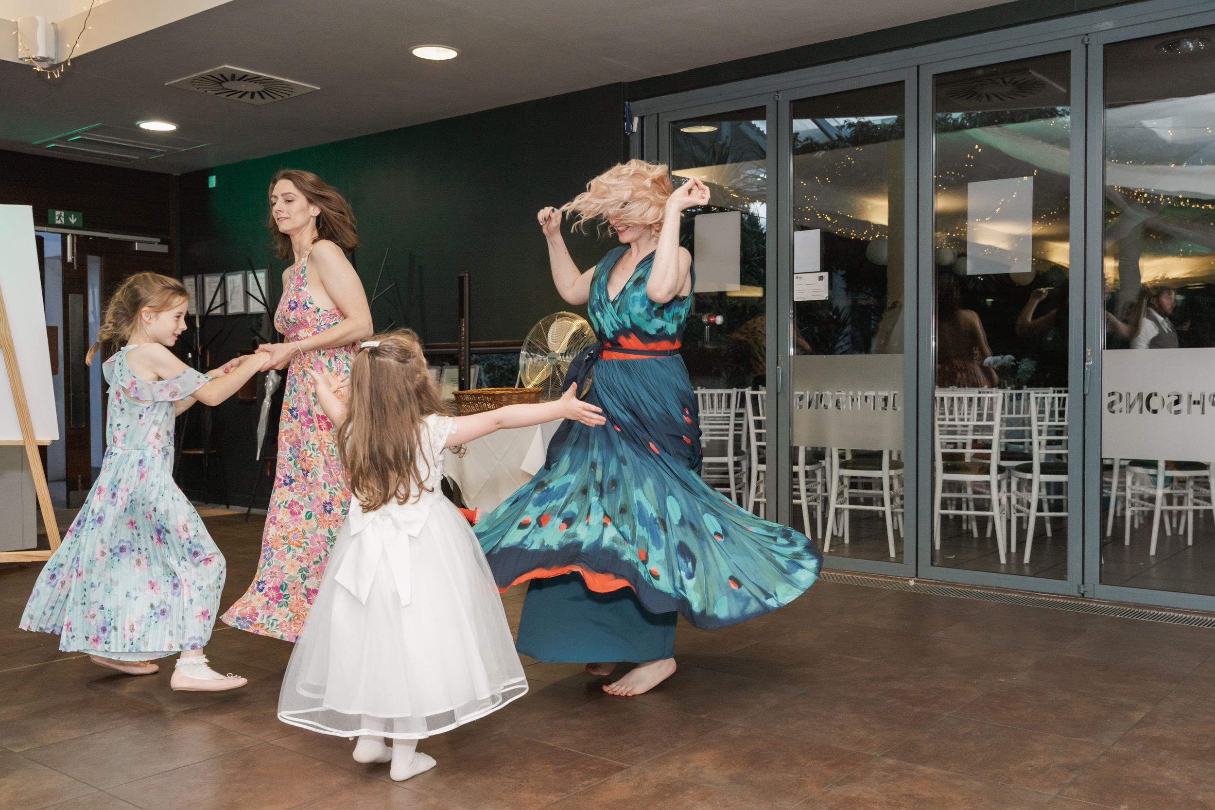 People dancing and twirling in vintage-style dresses at a celebration event.