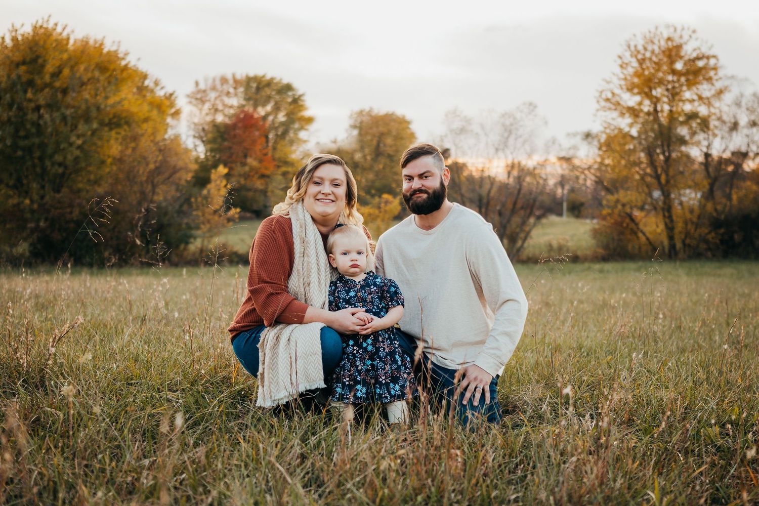 A heartwarming family moment captured in a golden autumn field during sunset.