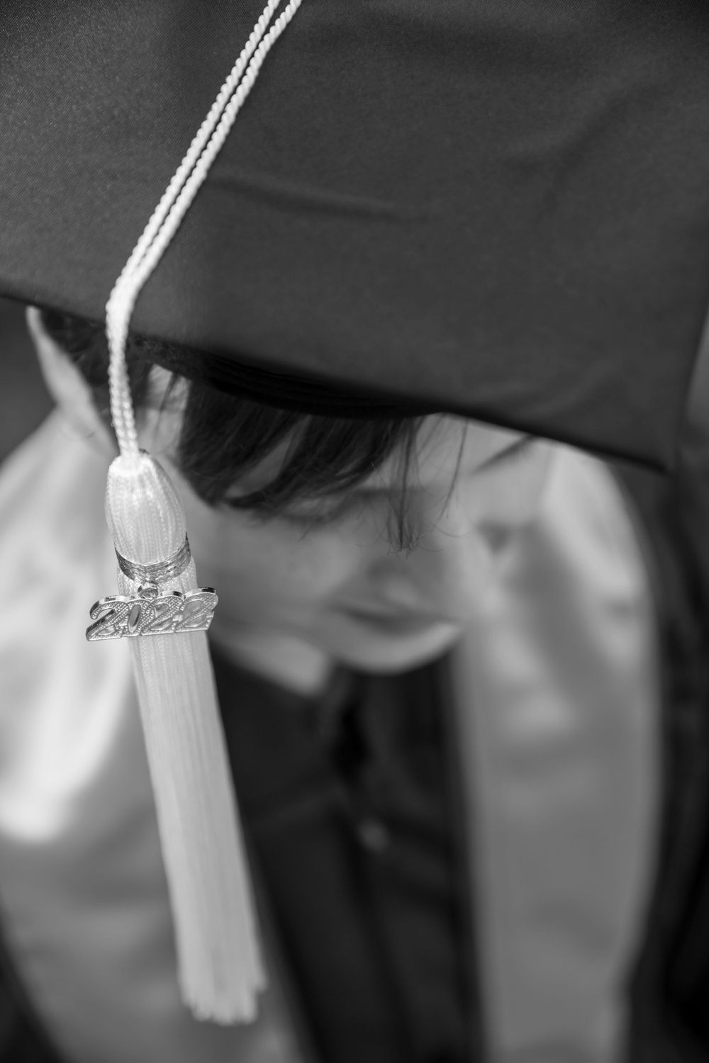 Close up shot of white graduation tassel against black graduation cap in black and white.