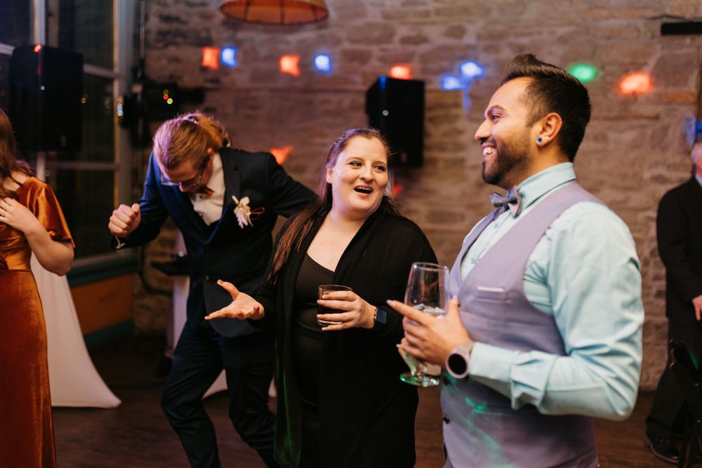 Joyful wedding guests laughing and dancing with champagne glasses at lively reception.