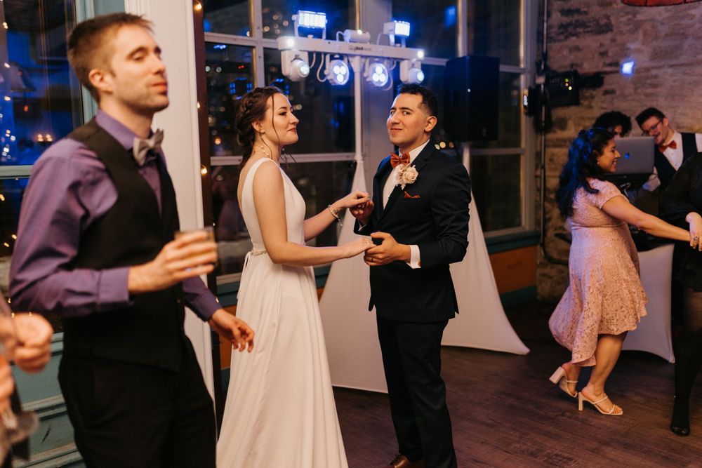 Bride in white gown and groom in suit dancing together at wedding reception.