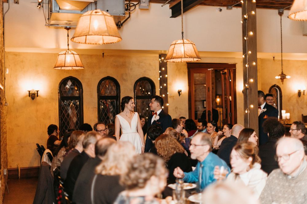 Bride and groom entering their elegant rustic wedding reception to applause from guests.