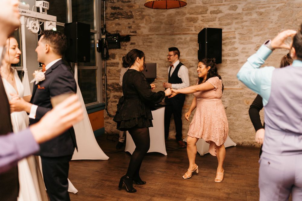 Guests dancing together on wooden dance floor at elegant wedding reception.