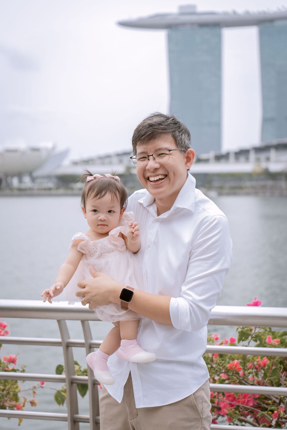 Parent and baby pose by Singapore's Marina Bay Sands on a cloudy day.