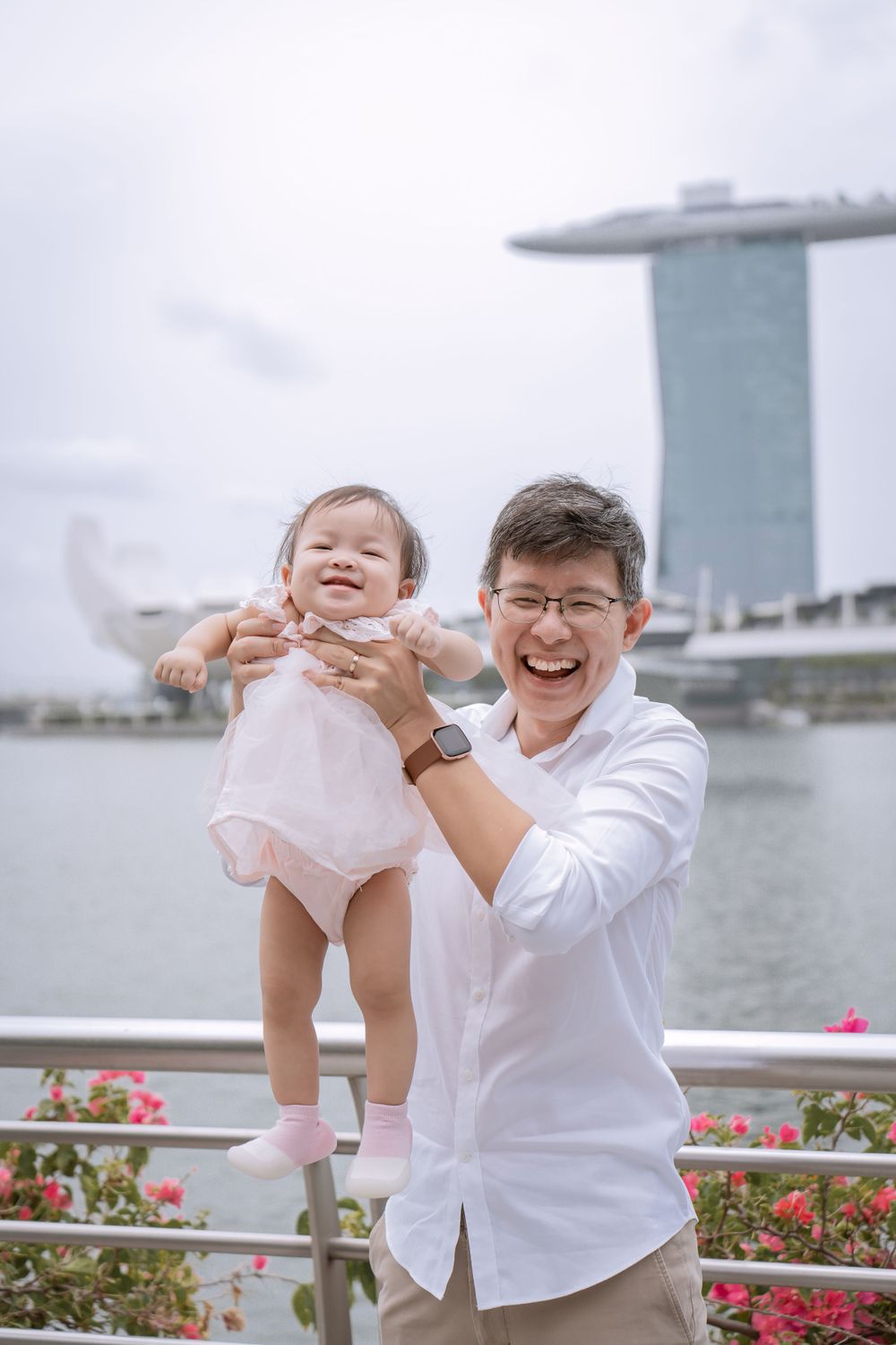Joyful parent and baby share a playful moment against Singapore's Marina Bay Sands backdrop.