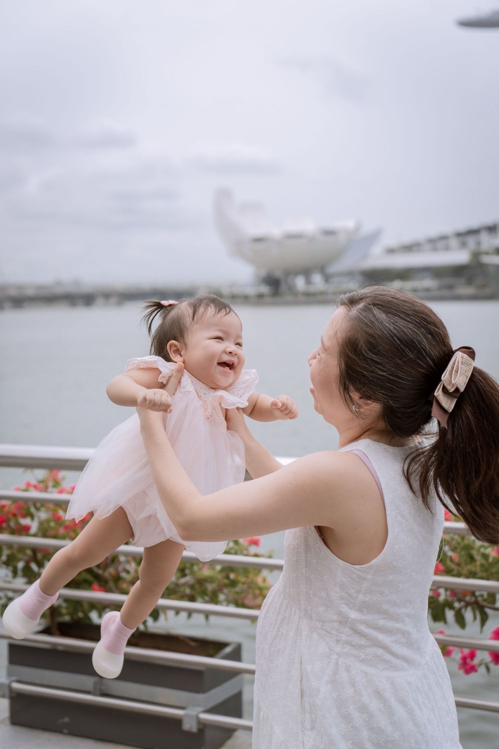 Playful moment between parent and laughing baby at Singapore's waterfront.