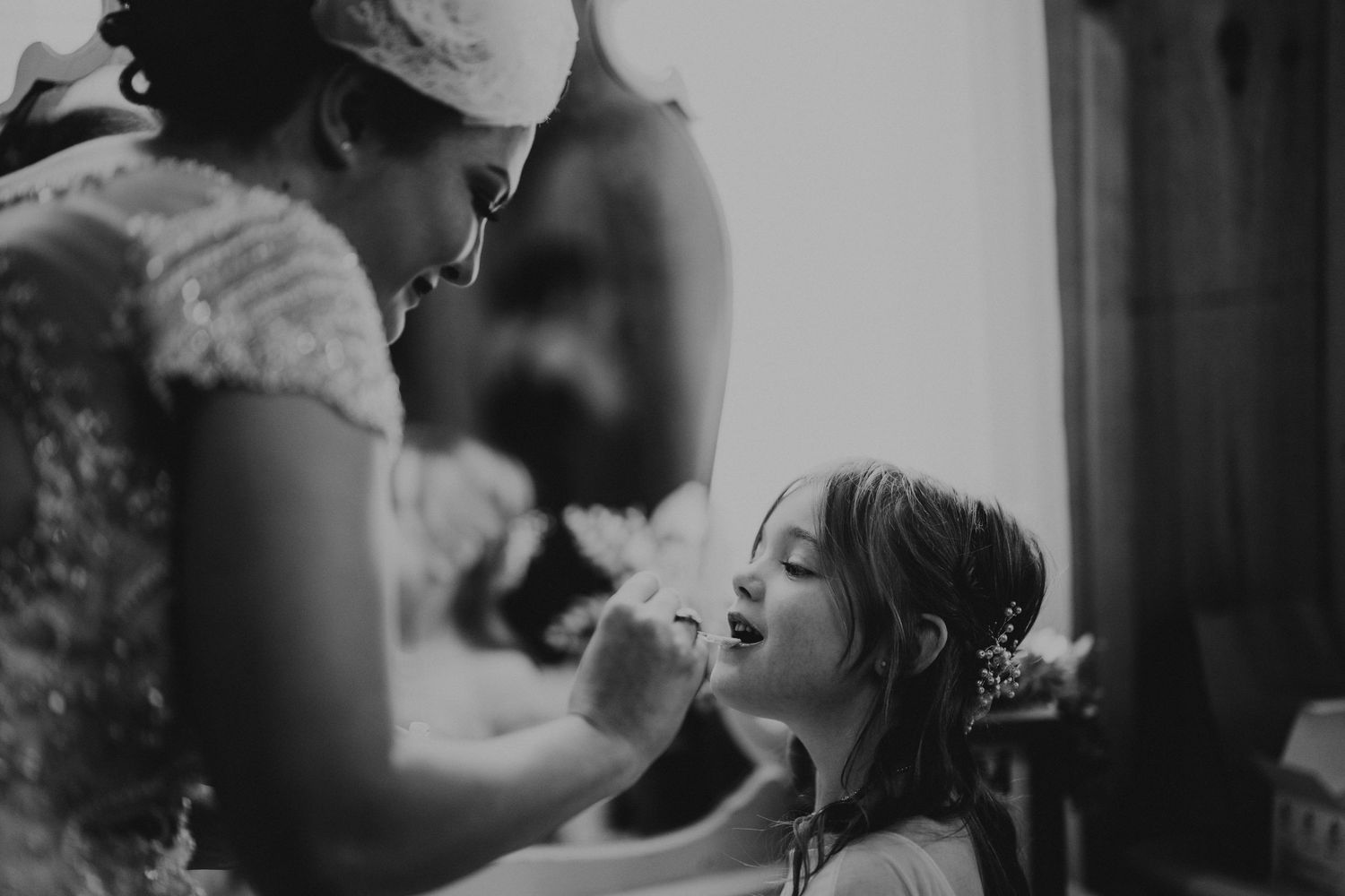Bride putting lip gloss on flower girl