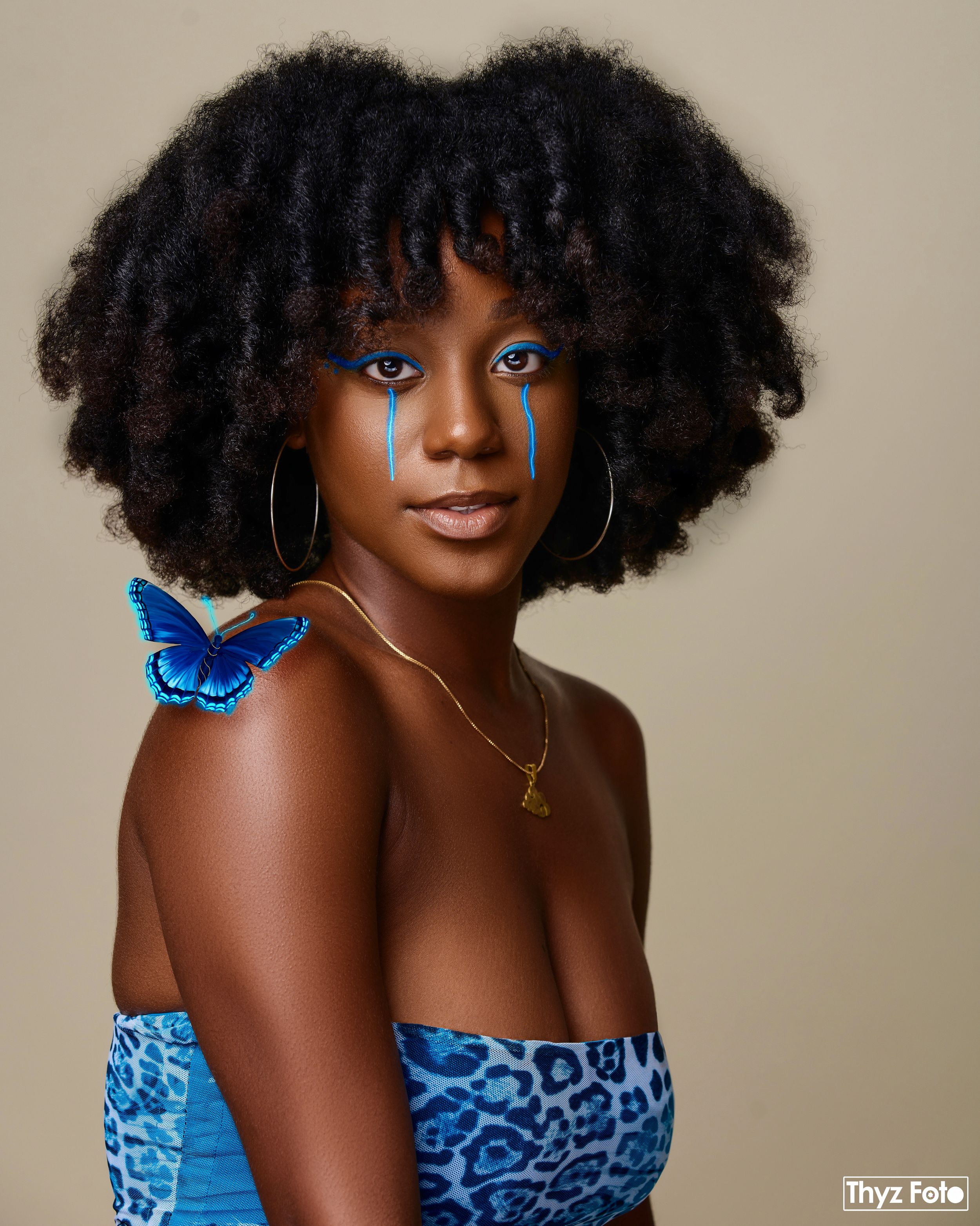 High-quality studio portrait featuring a model with voluminous natural curls, wearing a stylish blue top.