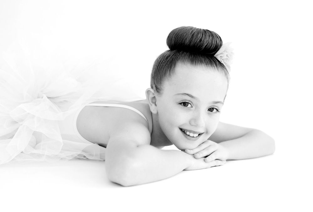 High key portrait of someone in dance attire resting on white background.
