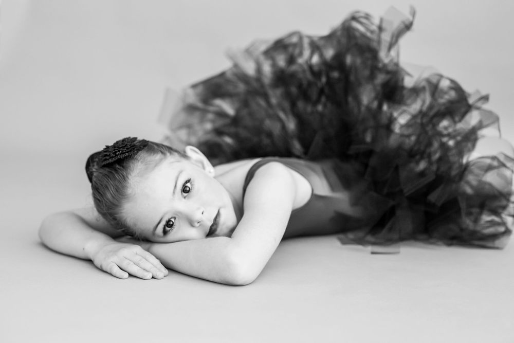 A dramatic black tulle dance costume creates contrast against a light studio background.