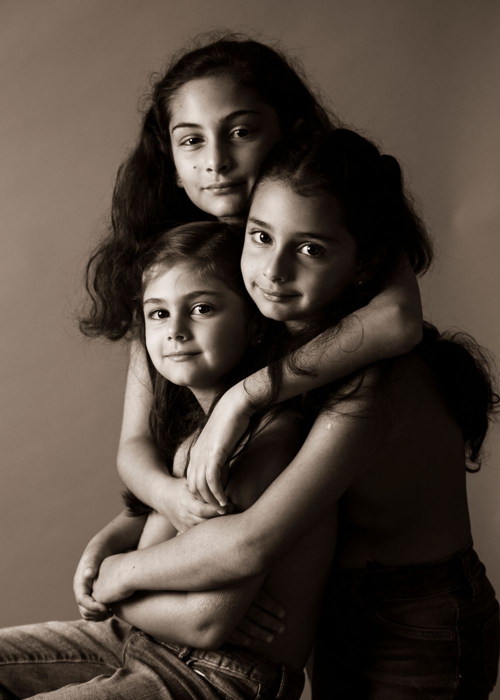 Artistic sepia portrait of three people sharing an intimate embrace.