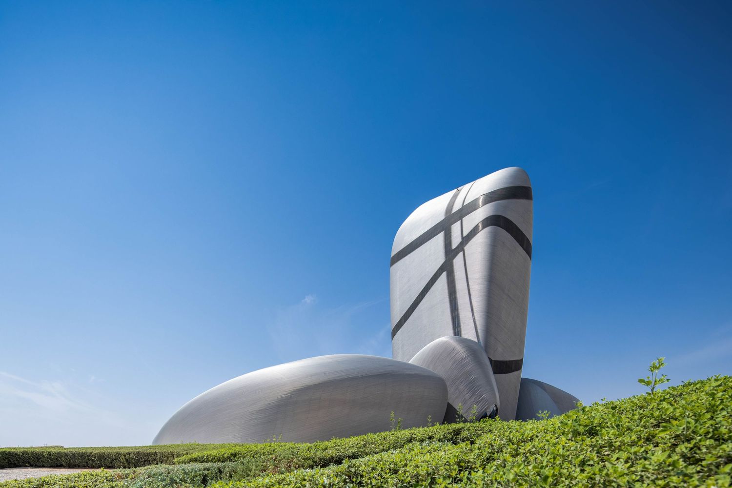 Futuristic white cultural center building with curved architecture against blue sky.