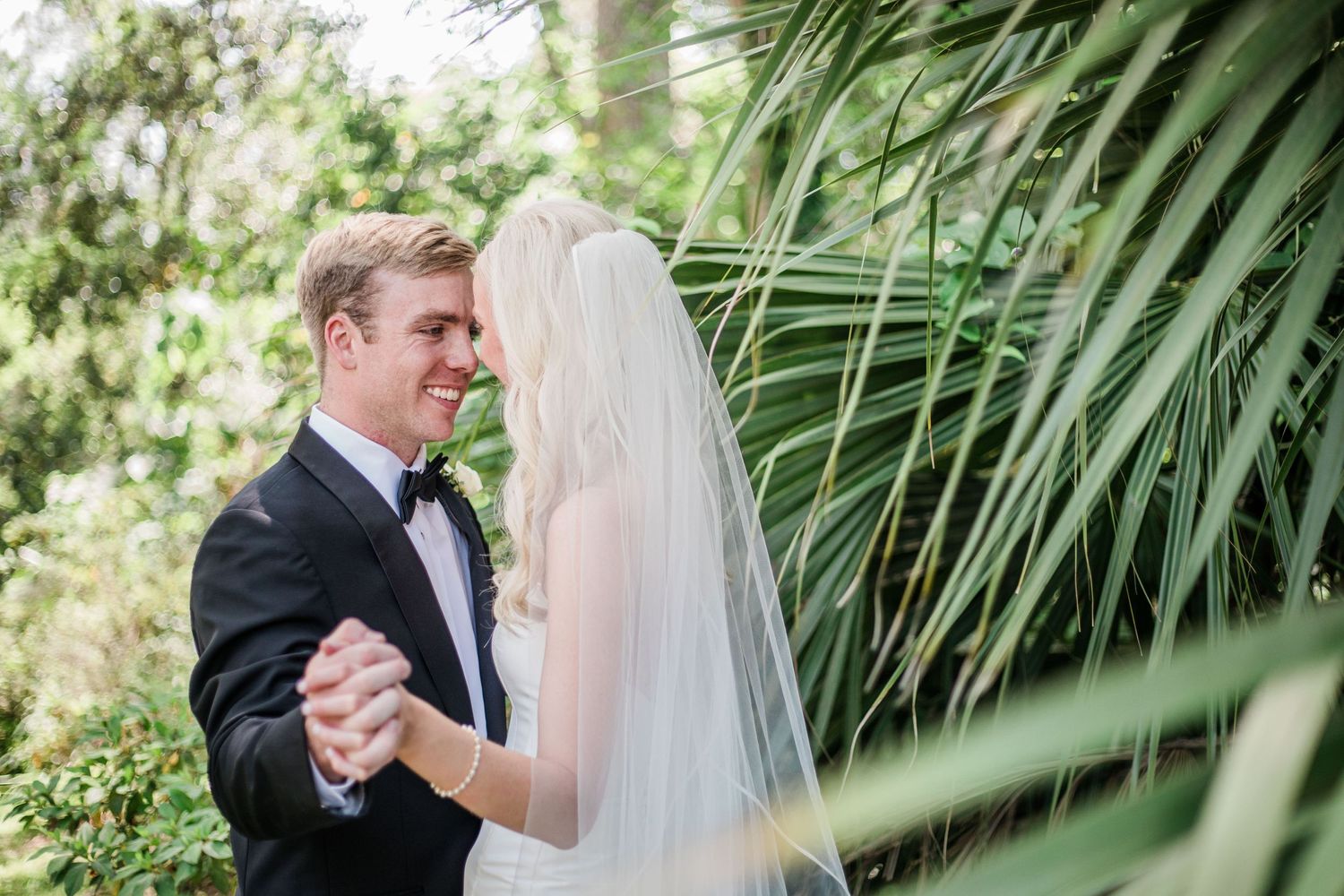 A romantic wedding moment captured through tropical palm fronds.
