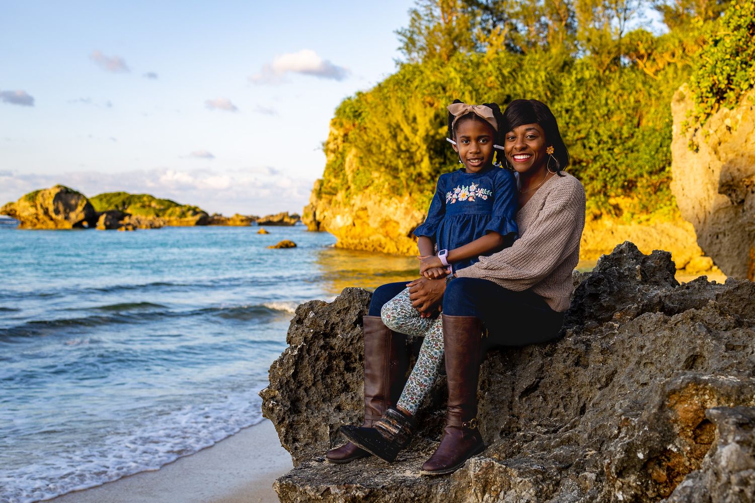 Two people sitting together on coastal rocks during golden hour by the ocean.