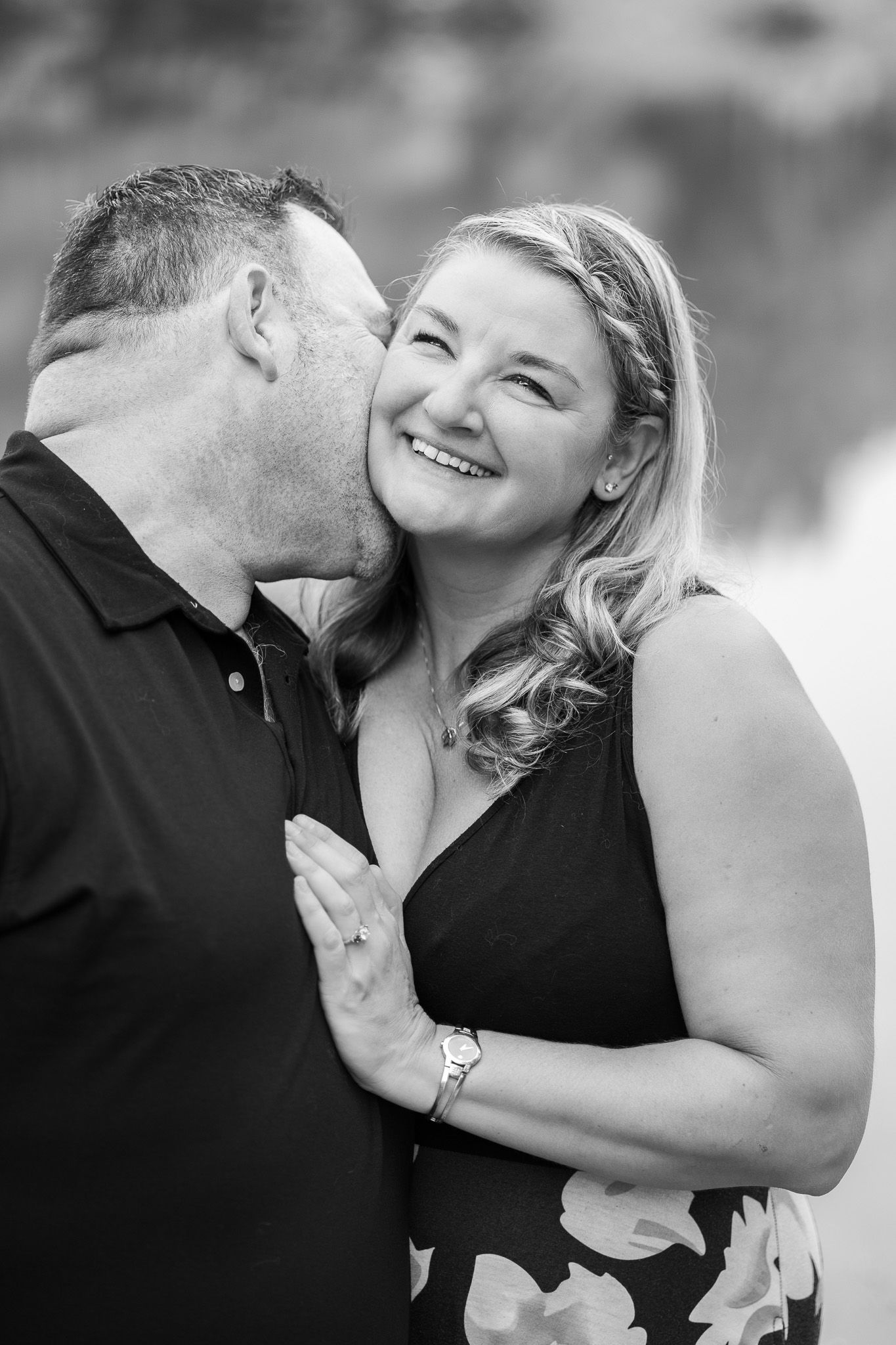A romantic black and white portrait of a couple sharing an affectionate moment.