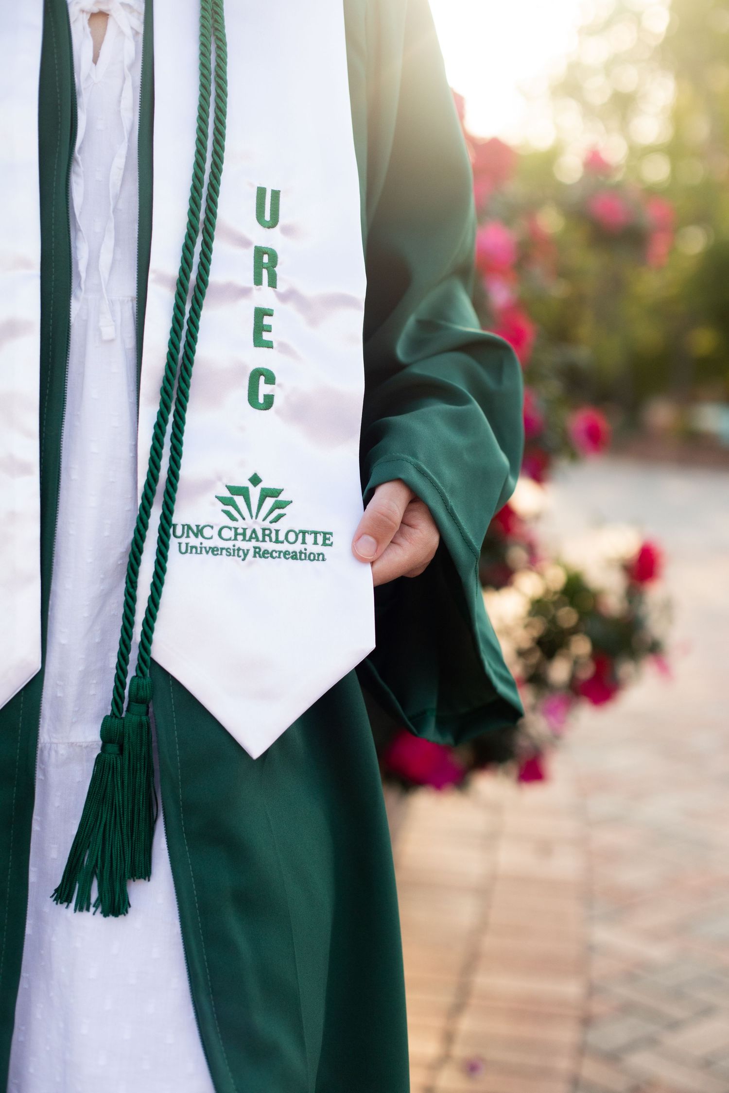 Detail shot of UNCC graduation stole with green cord against white gown.