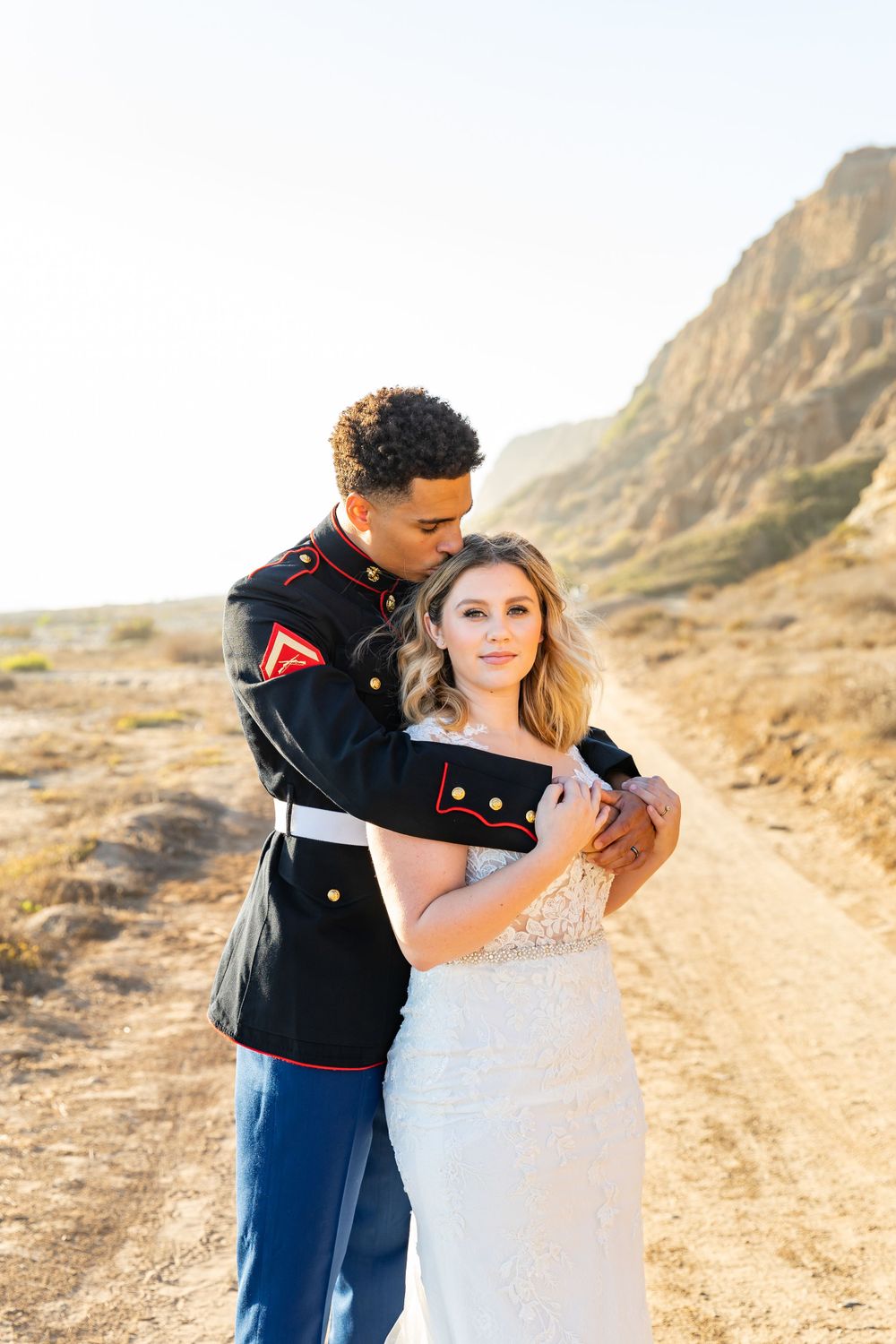 A tender moment between newlyweds against rugged desert cliffs during golden hour.